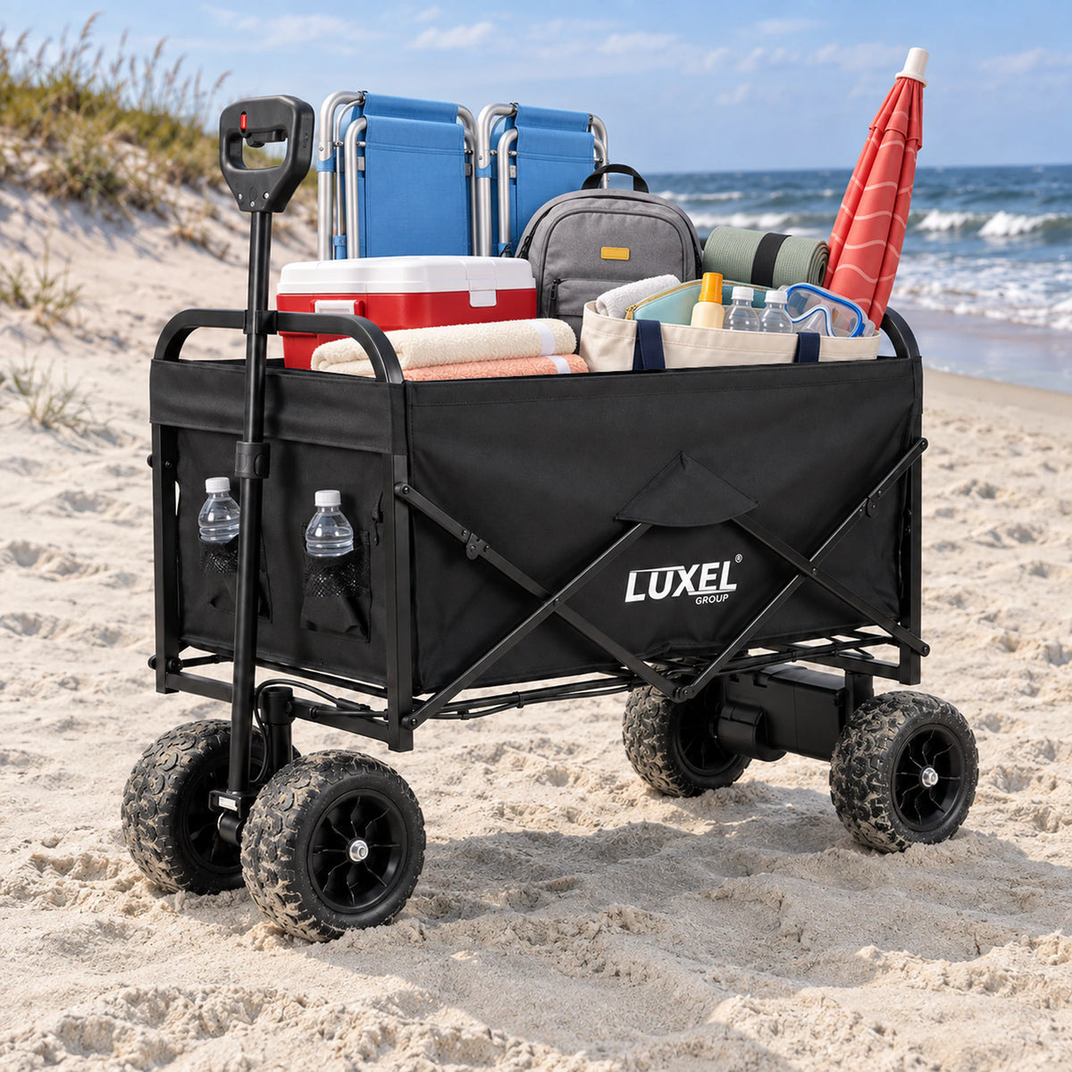 Black LUXEL electric wagon with off-road tires carrying beach chairs, a cooler, backpack, towels and a red umbrella on the beach.