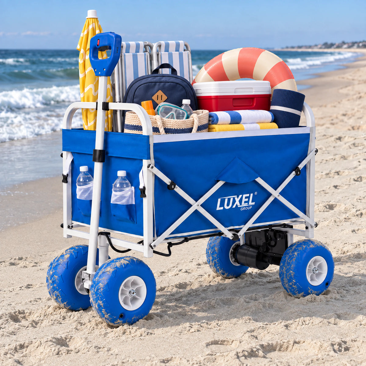 Blue LUXEL electric wagon carrying a folding chair, cooler, inflatable ring, backpack, towels and a yellow umbrella on the beach.